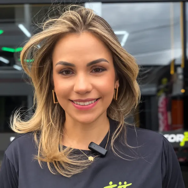 Integrante da DoctorFit sorrindo em frente ao estúdio com camisa do Summit 2025
