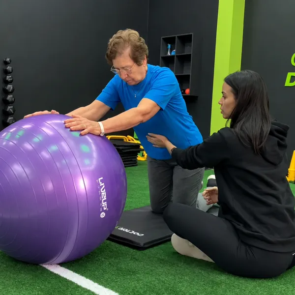Instrutora orientando aluna em exercício com bola suíça